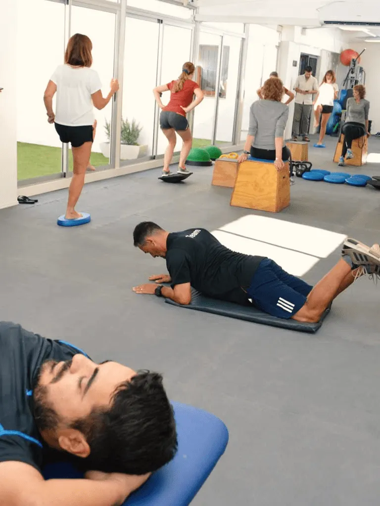 Varias personas realizando ejercicios terapéuticos en el gimnasio de la clínica