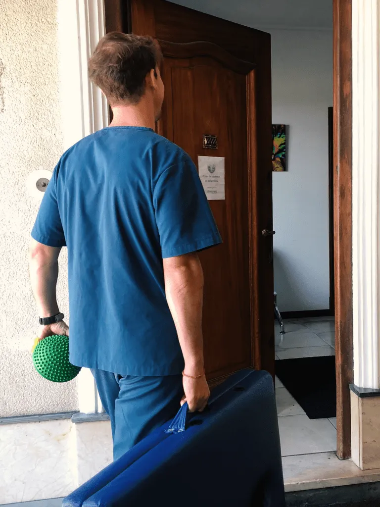 Fisioterapeuta con uniforme azul entrando a un domicilio con su equipo de trabajo