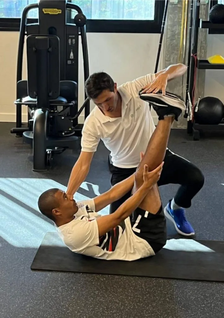 Fisioterapeuta asistiendo a un paciente en un ejercicio de elongación en el gimnasio de Profisio