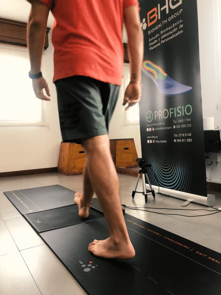 Persona caminando descalza sobre una plataforma de presión para un estudio biomecánico de la pisada