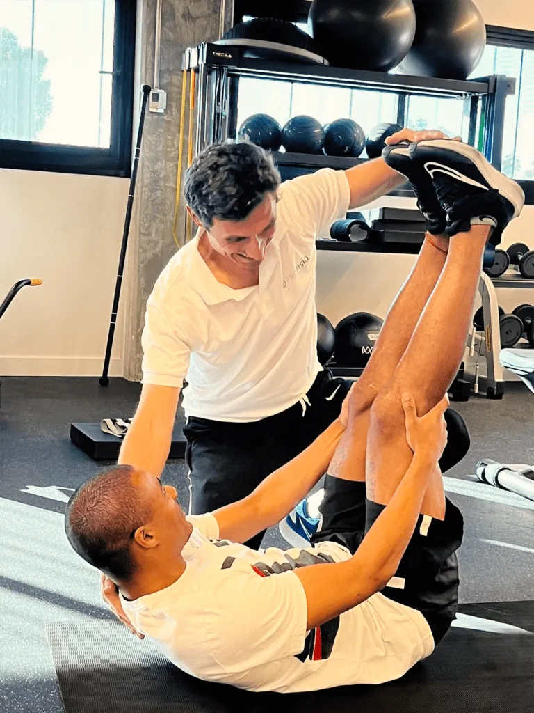 Fisioterapeuta guiando a un paciente en un ejercicio con las piernas elevadas en el gimnasio