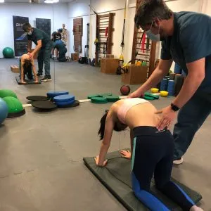 Fisioterapeuta guiando a una paciente en un ejercicio sobre una colchoneta
