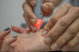 Aplicador de terapia con luz sobre la palma de la mano de un paciente