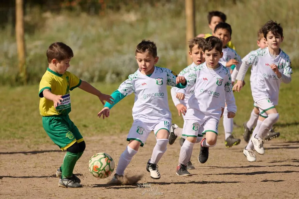 Niños jugando un partido de fútbol en una cancha de tierra