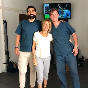 Tres personas posando juntas en la clínica, dos de ellas con uniforme azul
